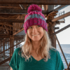 smiley blond long hair woman with purple striped bobble hat on under Brighton Palace pier