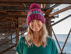 smiley blond long hair woman with purple striped bobble hat on under Brighton Palace pier